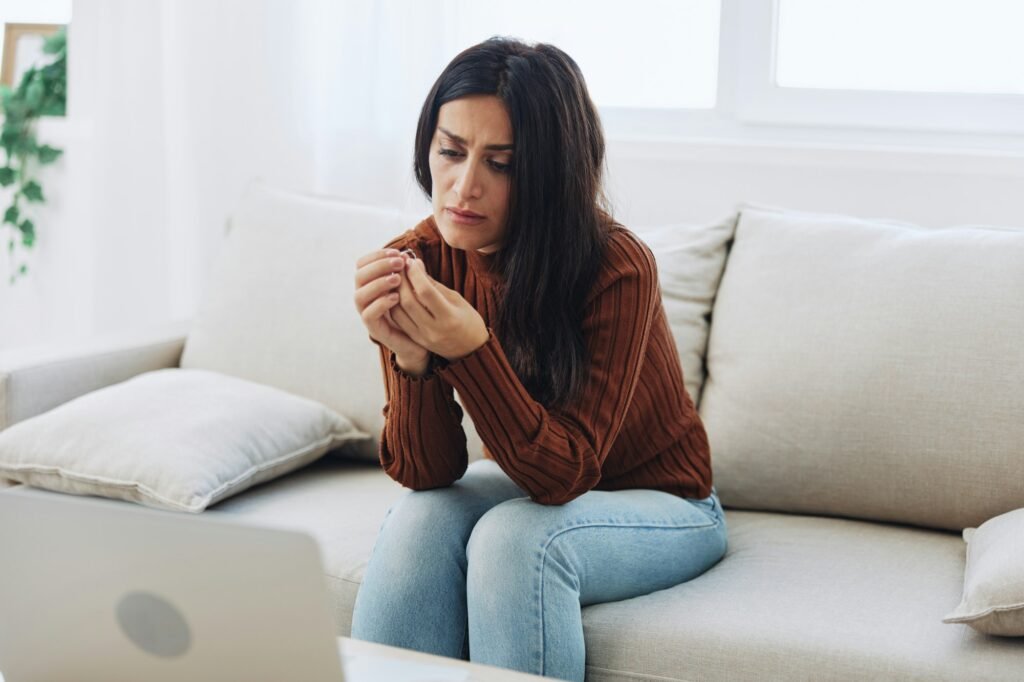 A woman looks sadly at a wedding ring in her hand, divorce and loss of a partner, breakup
