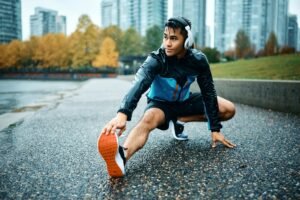 Young athlete stretching his leg during sports training outdoors in the rain.