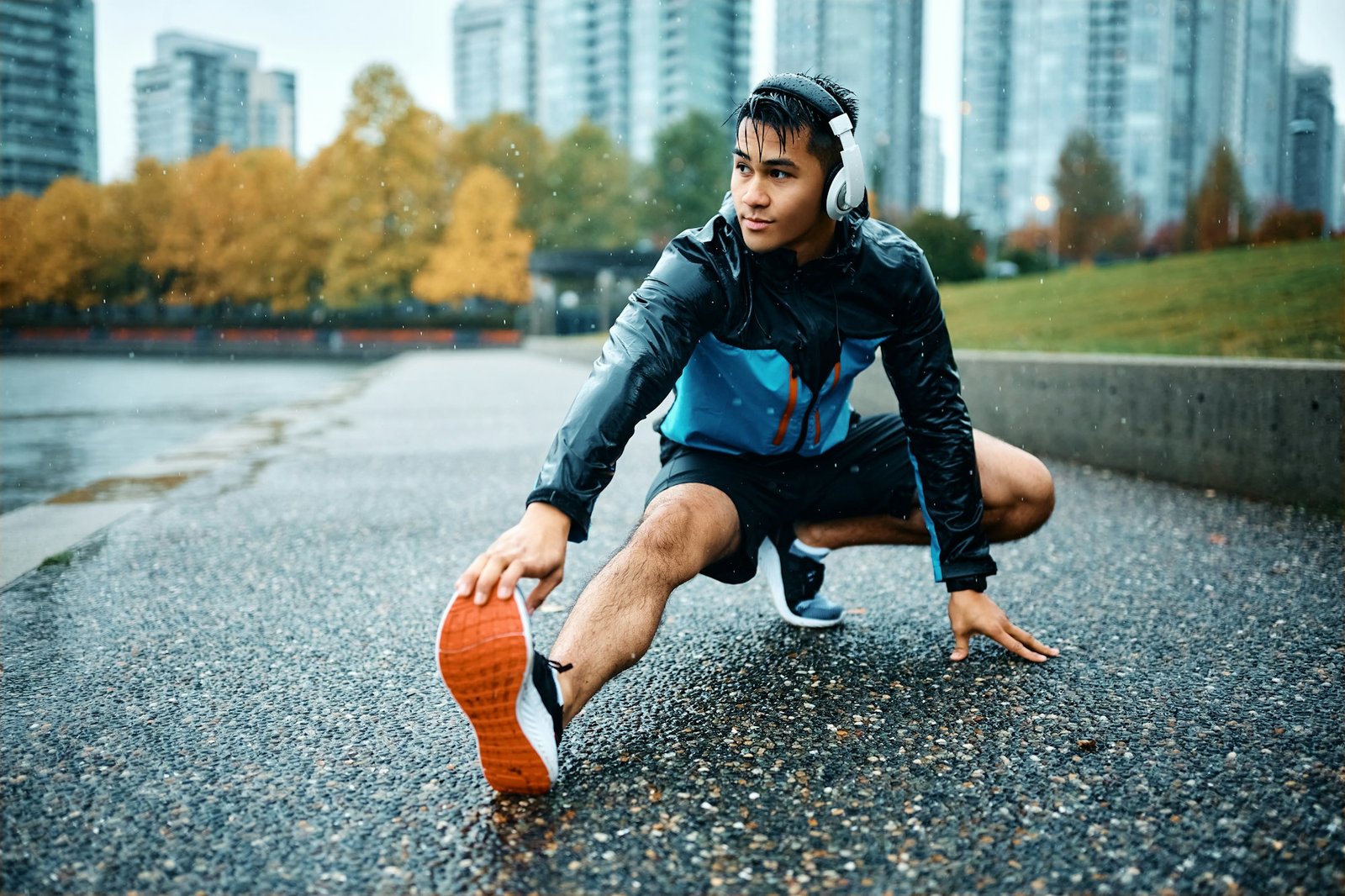 Young athlete stretching his leg during sports training outdoors in the rain.