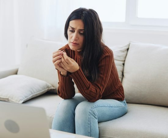 A woman looks sadly at a wedding ring in her hand, divorce and loss of a partner, breakup